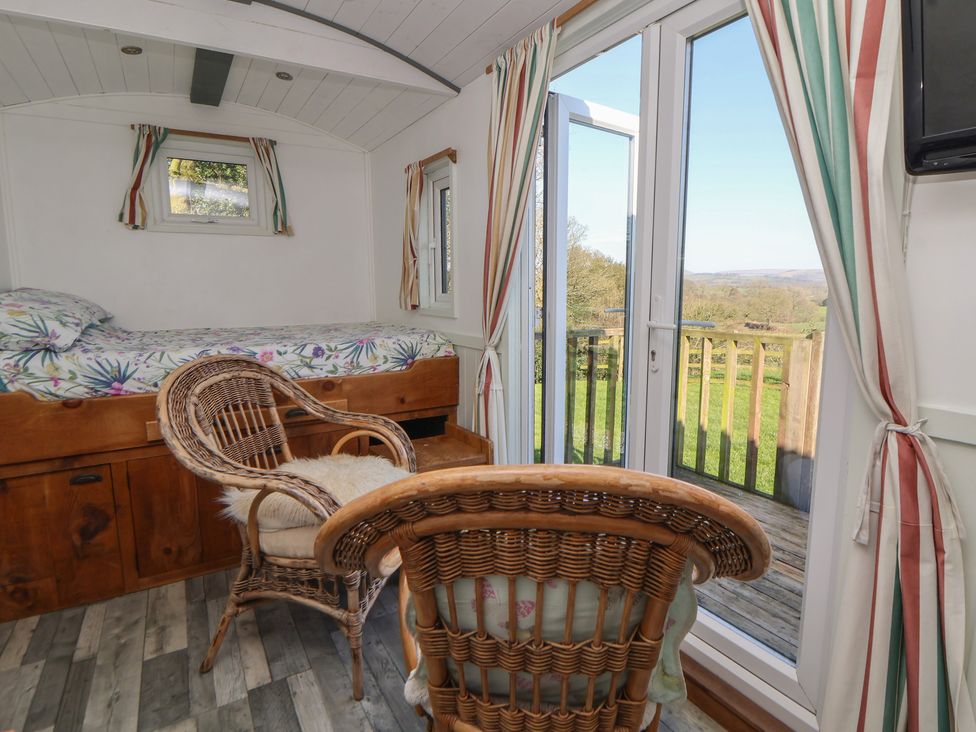 A bedroom with a bed and chairs at Shepherds Delight in Biddulph Moor