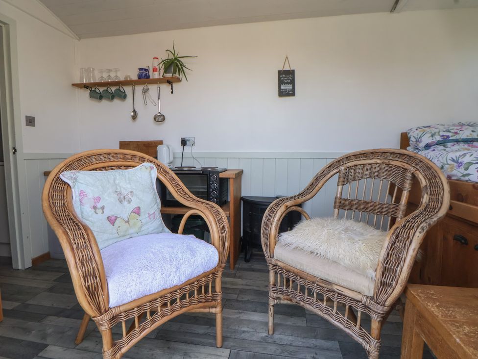 A living room with wicker chairs and a shelf at Shepherds Delight in Biddulph Moor