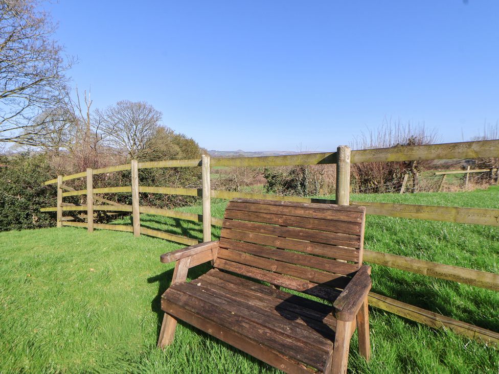 A bench in a garden with a fence and trees at Shepherds Delight in Biddulph Moor