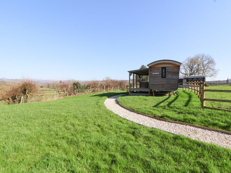 A wooden cabin with a gravel path in a grassy area at Golden Fleece in Biddulph Moor