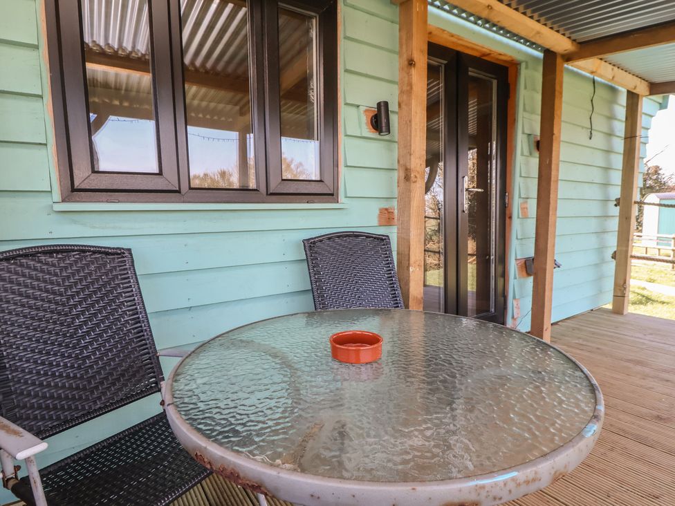 An outdoor seating area with a glass table and chairs at Golden Fleece in Biddulph Moor