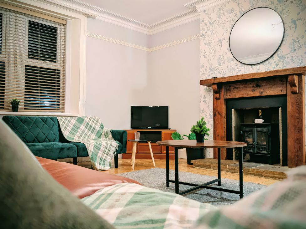 A living room with a sofa, television, and coffee table at 4 The Croft in Hexham