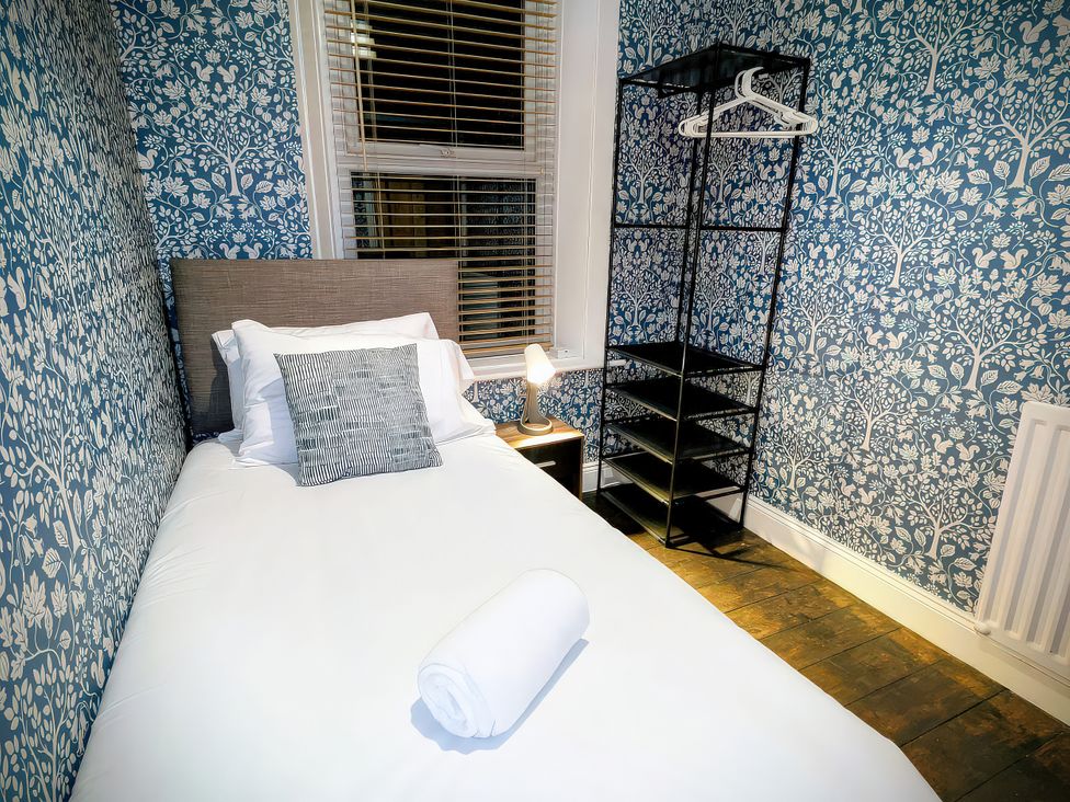 A bedroom with a bed and a shelving unit at 4 The Croft in Hexham