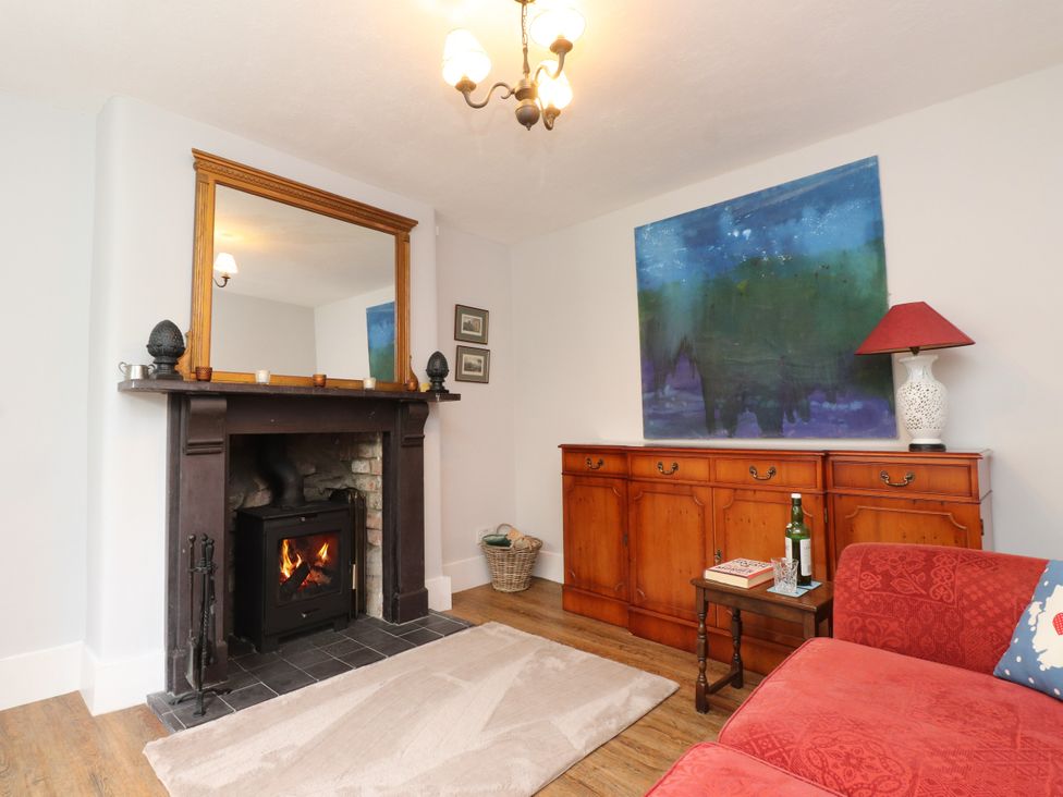 A living room with a fireplace and sideboard at 3 Tre Felin Llandygai near Bangor