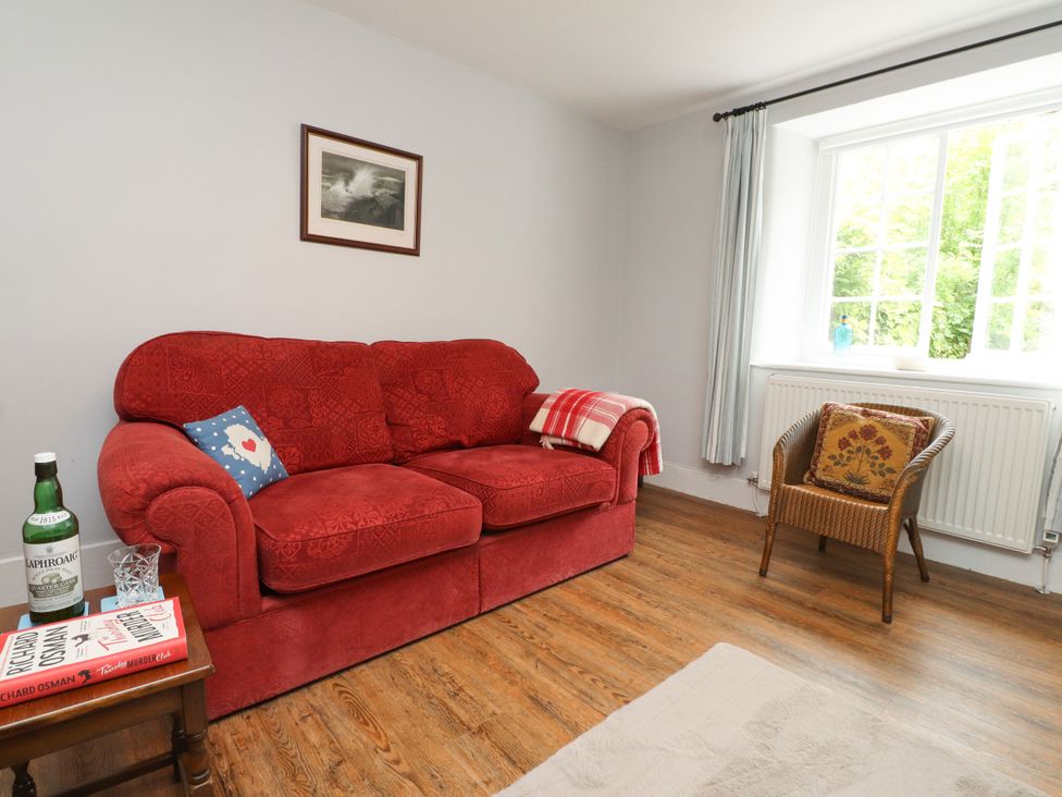 A living room with a red sofa and coffee table at 3 Tre Felin in Llandygai near Bangor