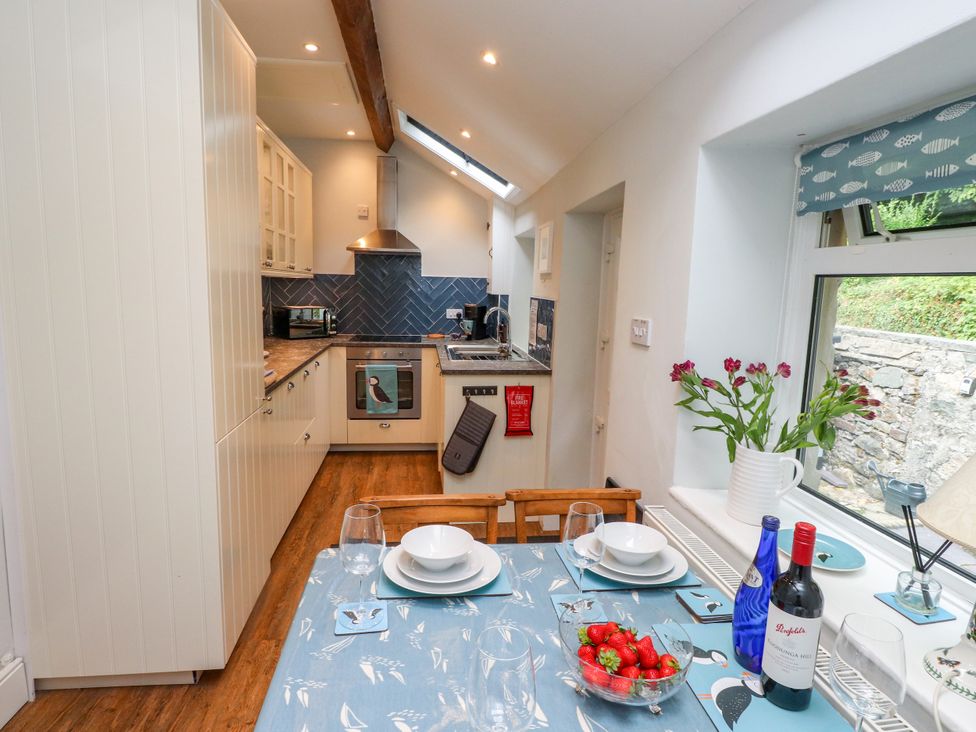 A kitchen with a dining table and wine bottles at 3 Tre Felin in Llandygai near Bangor
