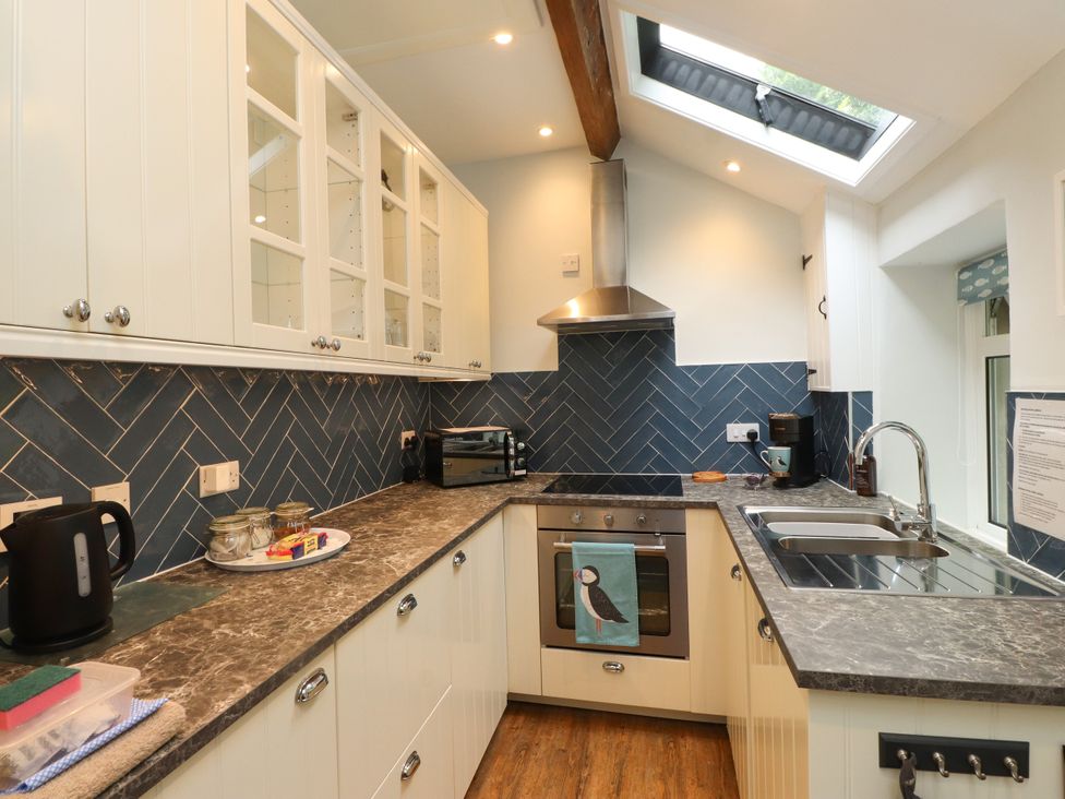 A kitchen with cabinets, a sink and kitchen appliances at 3 Tre Felin in Llandygai near Bangor