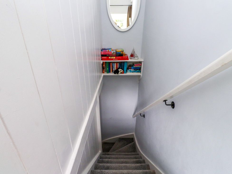 A staircase with a bookshelf and a mirror at 3 Tre Felin in Llandygai near Bangor