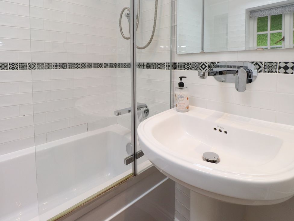 A bathroom with a bathtub, shower, sink and mirror at 3 Tre Felin in Llandygai near Bangor