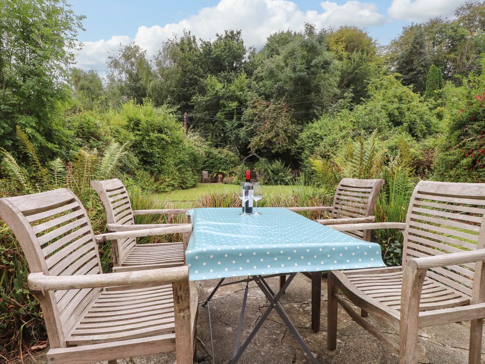 A table with chairs and a bottle in a garden at 3 Tre Felin in Llandygai near Bangor