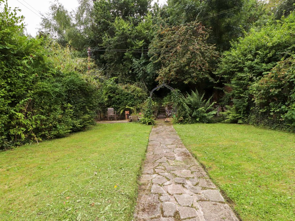 A garden with a stone pathway leading to a seating area at 3 Tre Felin in Llandygai near Bangor