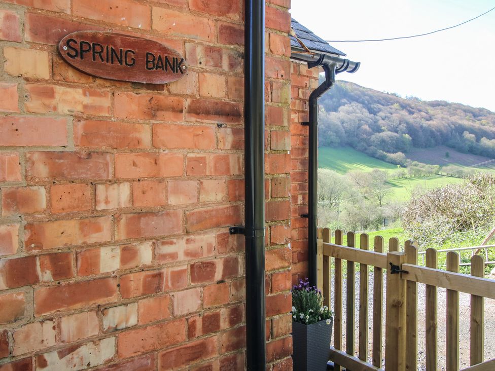 A brick wall with a sign and a fence leading to a view at Spring Bank in Llanfyllin