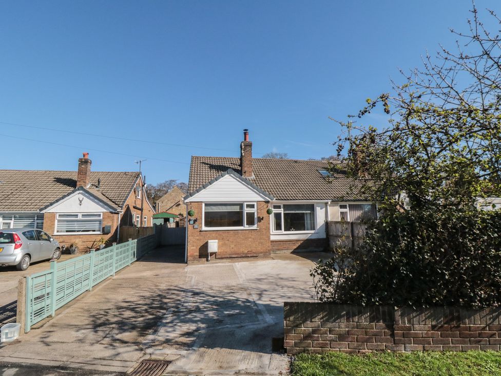 A bungalow with a driveway and fence at Coastal Retreat in Scarborough