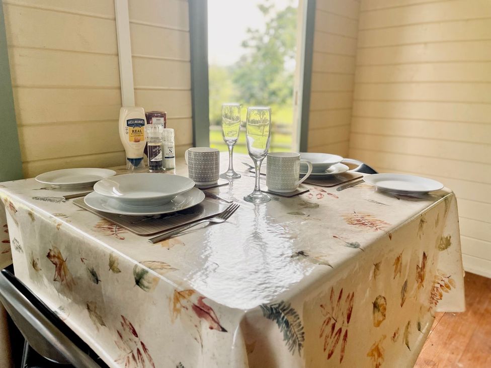 A dining room table set with plates and glasses at Cwt Tyddyn Shepherd's Hut in Corwen