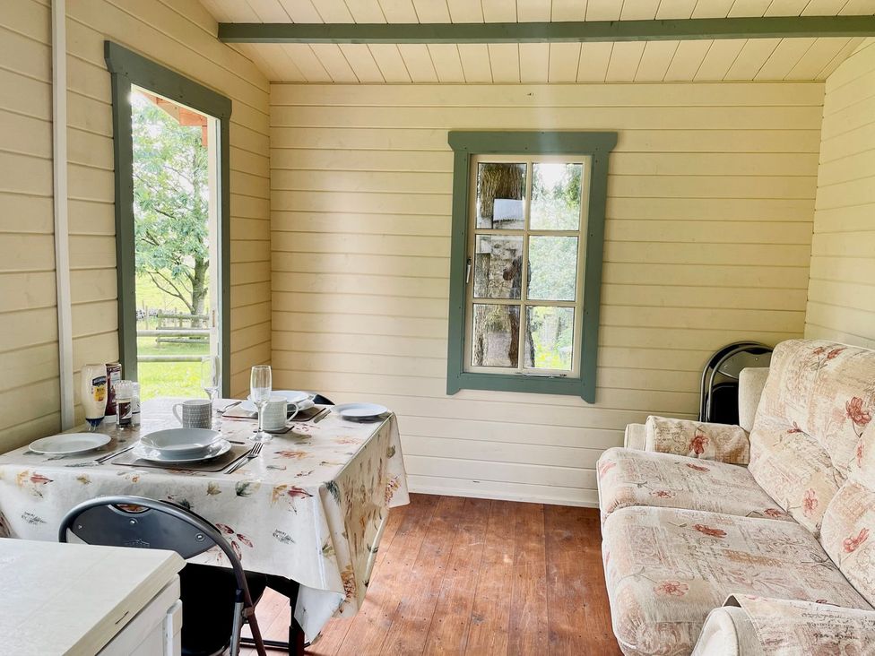 An indoor dining area with a table and couch at Cwt Tyddyn Shepherd's Hut in Corwen
