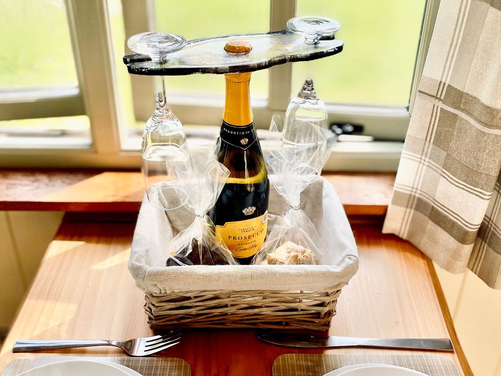 A basket with a wine bottle, glasses and snacks at Cwt Tyddyn Shepherd's Hut in Corwen
