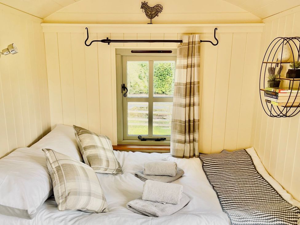 A bedroom with a bed and a window at Cwt Tyddyn Shepherd's Hut in Corwen