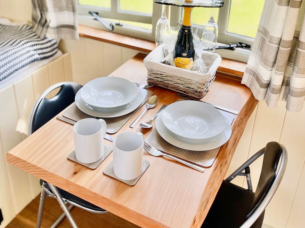 A dining table set with plates and mugs at Cwt Tyddyn Shepherd's Hut in Corwen