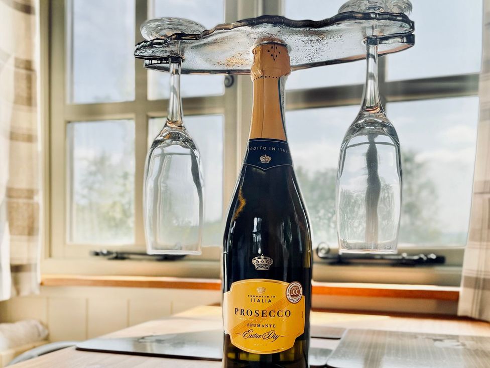 A Prosecco bottle with wine glasses on a table at Cwt Tyddyn Shepherd's Hut in Corwen