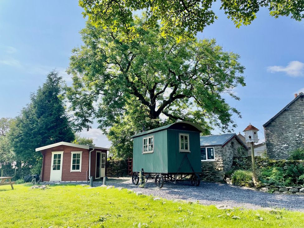 A shepherd's hut and a red cabin outside at Cwt Tyddyn Shepherd's Hut in Corwen