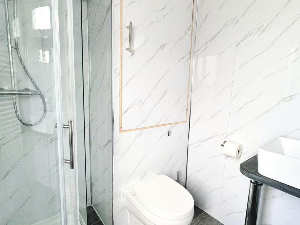 A bathroom with a shower, toilet, and sink at Cwt Tyddyn Shepherd's Hut in Cefn Brith near Cerrigydrudion