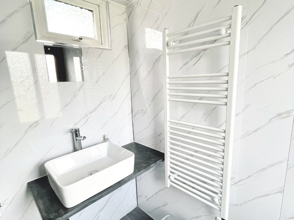 A bathroom with a sink and towel radiator at Cwt Tyddyn Shepherd's Hut in Cefn Brith near Cerrigydrudion
