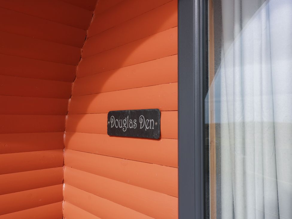 A sign labeled Douglas Den on an orange wall at Douglas in Stoneykirk near Sandhead
