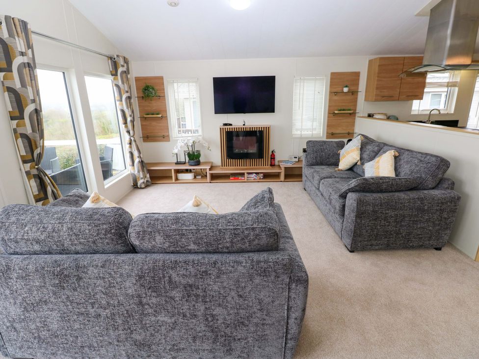 A living room with sofas and a television at Wernlas Lodge in Oxwich