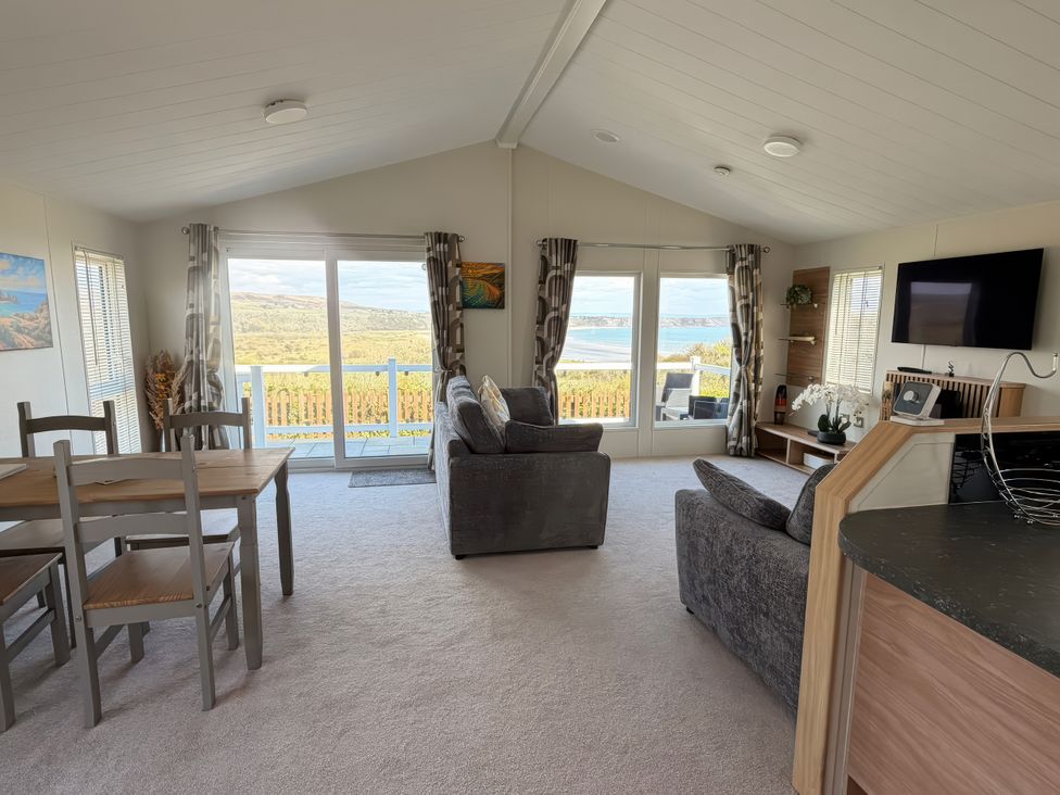 A living room with a sofa and dining table at Wernlas Lodge in Oxwich