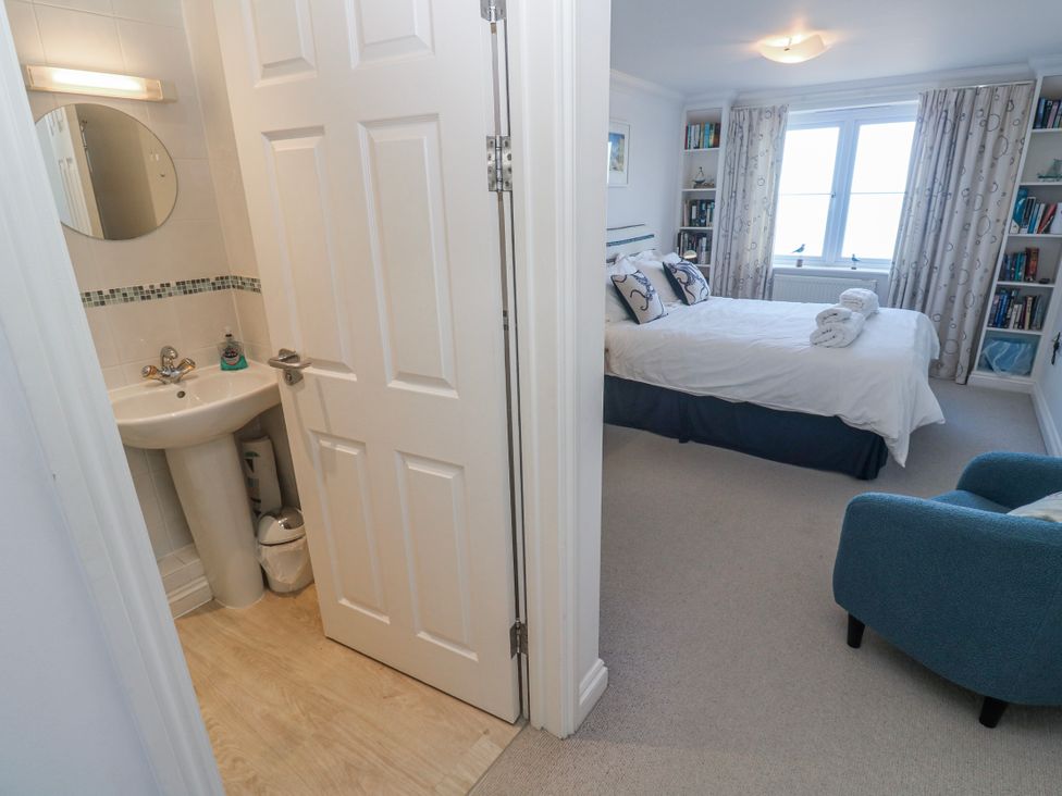 A bedroom with a bed, chair, and shelf at 21 Compass Point in Carbis Bay