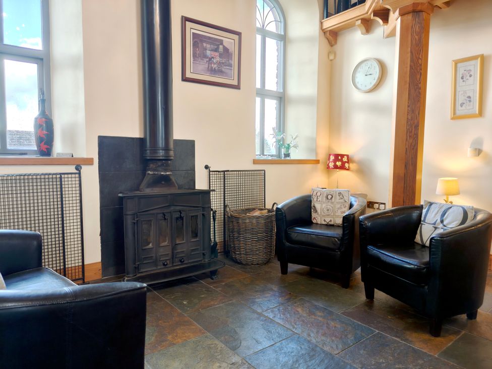 A living room with a wood stove and armchairs at Kaber Chapel in Kaber near Kirby Stephen