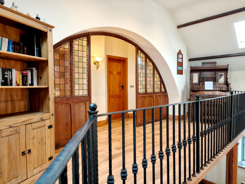 A hallway with a bookshelf and ornate wooden cabinet at Kaber Chapel in Kaber near Kirby Stephen