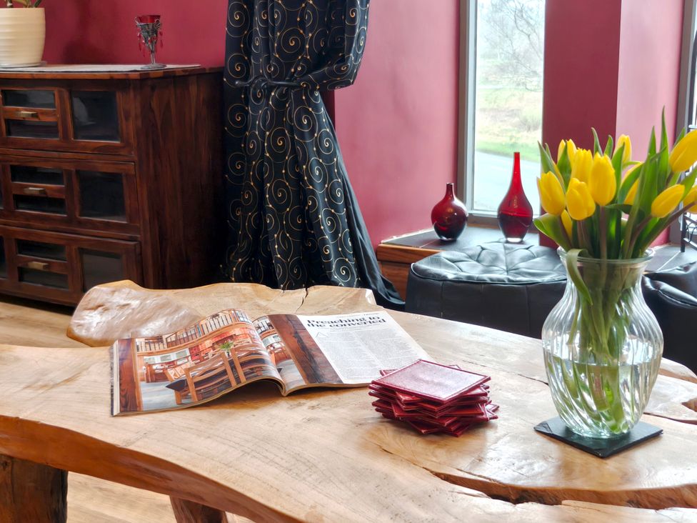 A living room with a magazine and a vase of flowers at Kaber Chapel in Kaber near Kirby Stephen