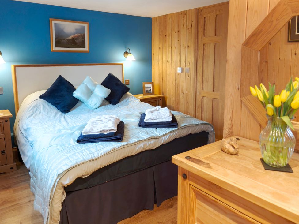 A bedroom with a bed, bedside table, and flowers in a vase at Kaber Chapel near Kirby Stephen