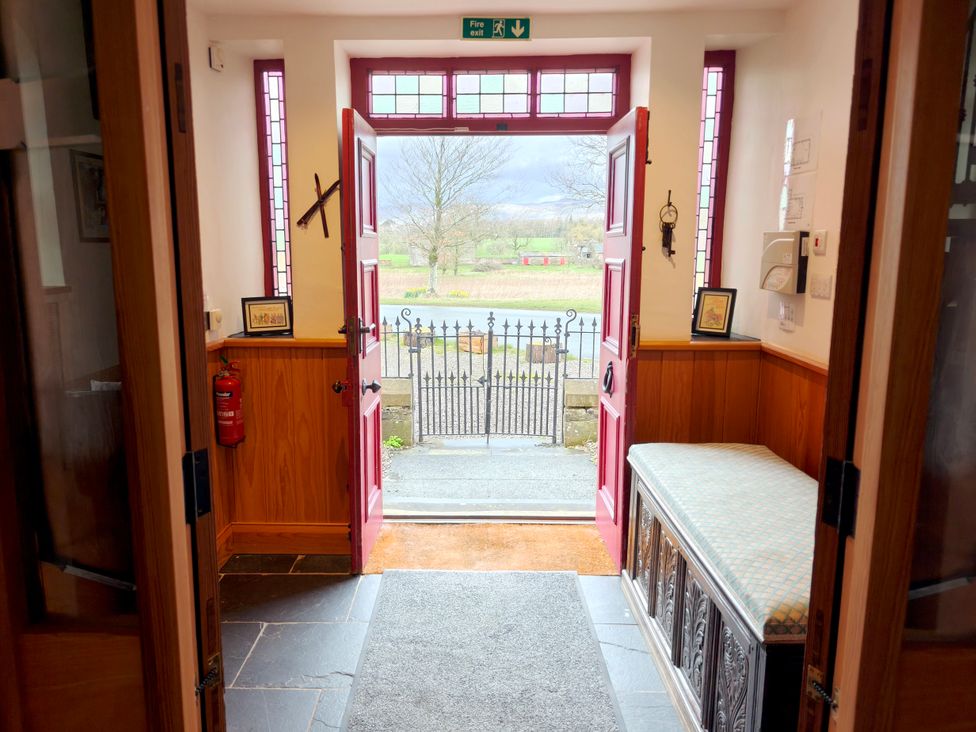 An entrance with red front doors and a bench at Kaber Chapel near Kirby Stephen