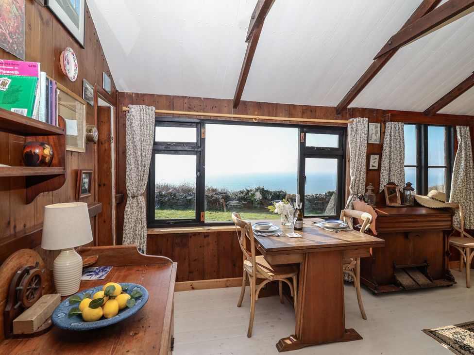 A dining room with a table and chairs overlooking the sea at The Cabin