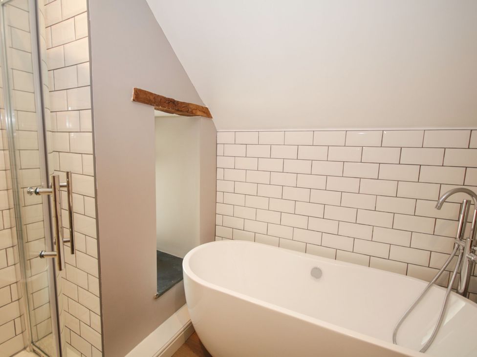 A bathroom with a bathtub and shower area at Sun Trevor Barns 2 in Llangollen