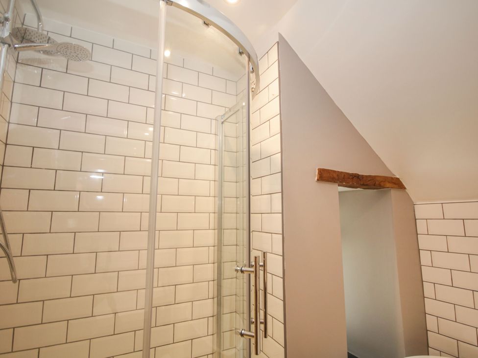 A shower with glass door and tiled walls at Sun Trevor Barns 2 Llangollen