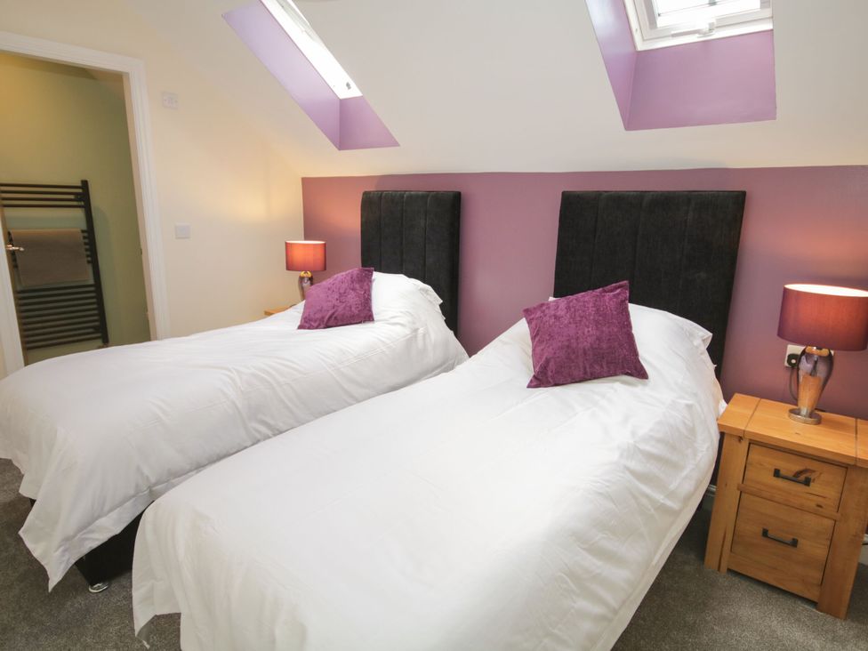 A bedroom with two beds and a bedside table at Sun Trevor Barns 2 Llangollen
