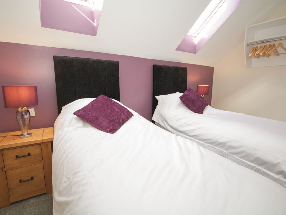 A bedroom with two beds and a bedside table at Sun Trevor Barns 2, Llangollen