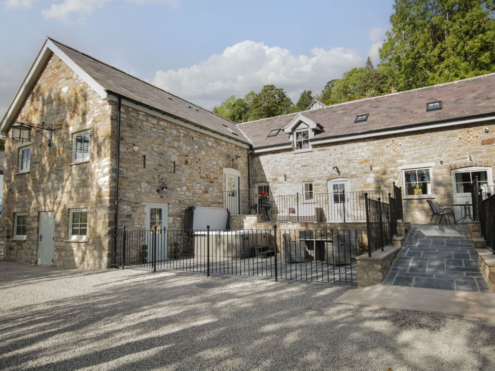 An outdoor view of a stone building with a fence and steps at Sun Trevor Barns 3, Llangollen
