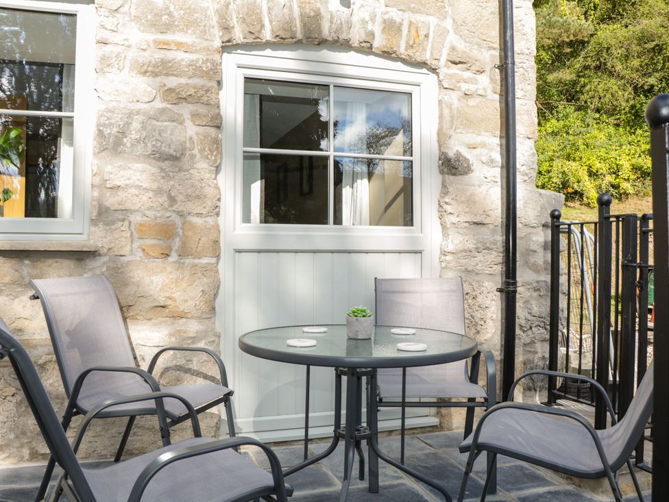 An outdoor seating area with a table and chairs at Sun Trevor Barns 3 Llangollen