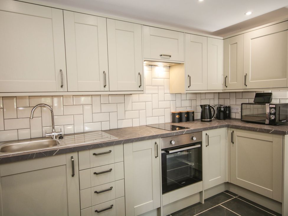 A kitchen with cabinets, sink, oven, kettle, and microwave at Sun Trevor Barns 3 in Llangollen