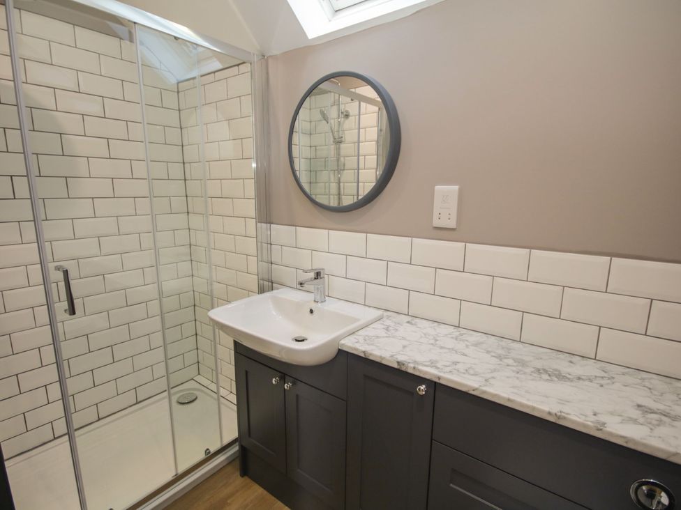 A bathroom with a shower, sink, and mirror at Sun Trevor Barns 3, Llangollen