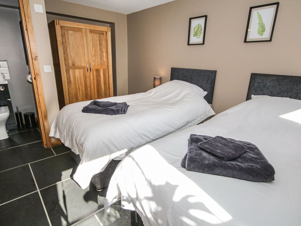 A bedroom with two beds and a wardrobe at Sun Trevor Barns 3 in Llangollen
