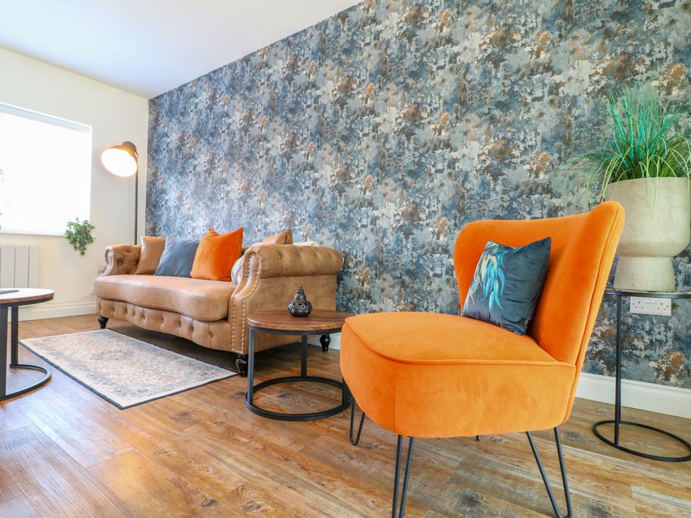 A living room with a sofa and armchair at 19 Berry Avenue in Breedon On The Hill