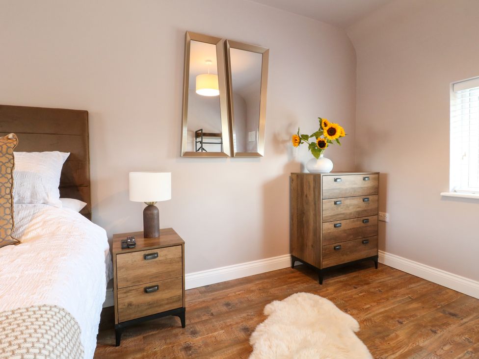 A bedroom with a bed, nightstand, and a chest of drawers at 19 Berry Avenue, Breedon On The Hill