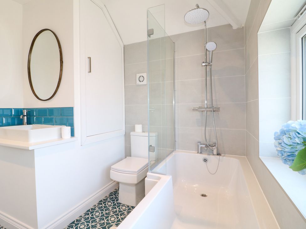 A bathroom with a bathtub, shower, and sink at 19 Berry Avenue in Breedon On The Hill