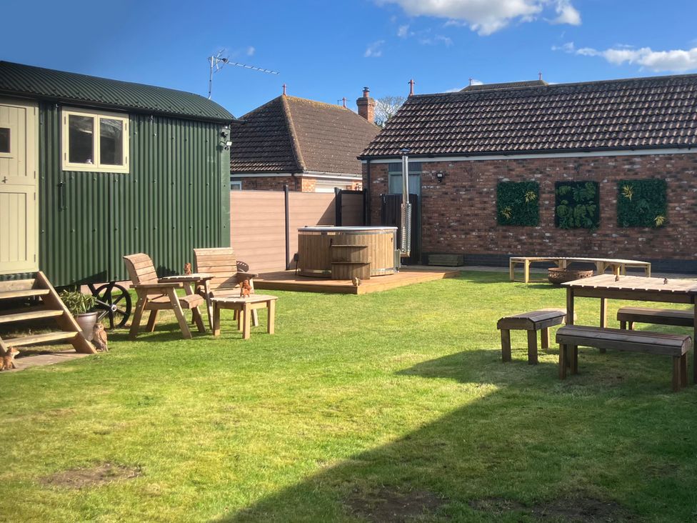 A garden with a shepherd hut and hot tub at Twit Twoo Shepherds Hut North Somercotes