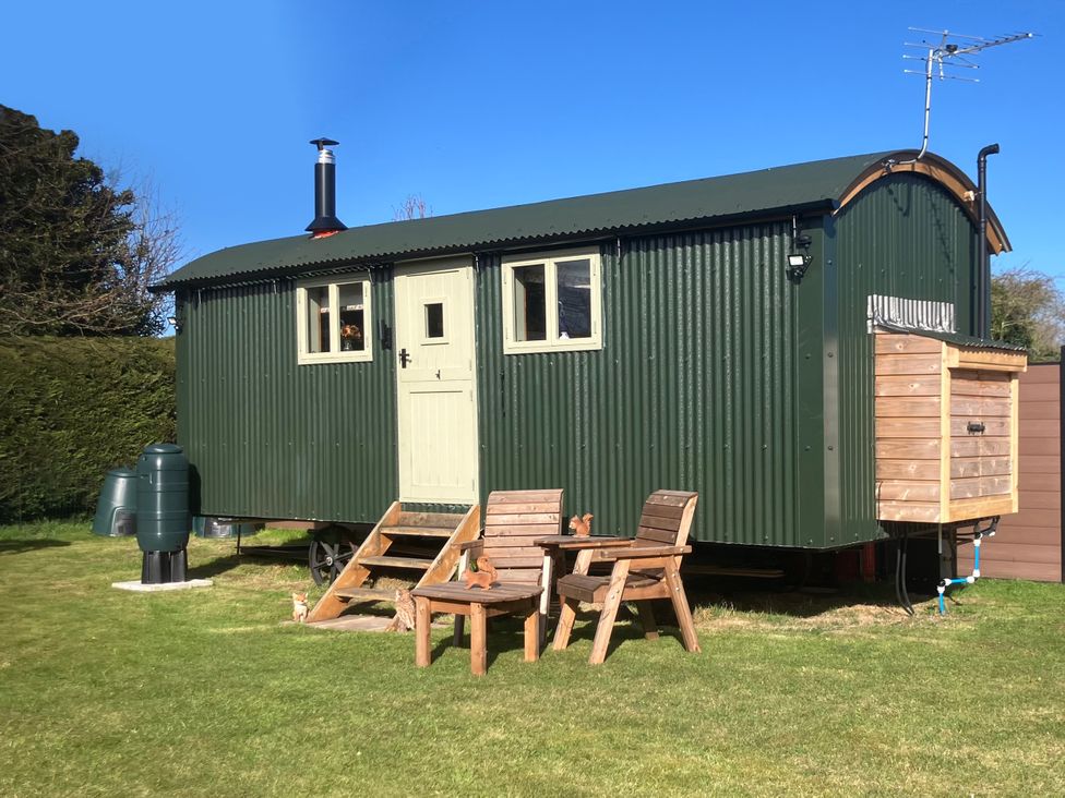A shepherd's hut with chairs and a water tank at Twit Twoo Shepherds Hut North Somercotes